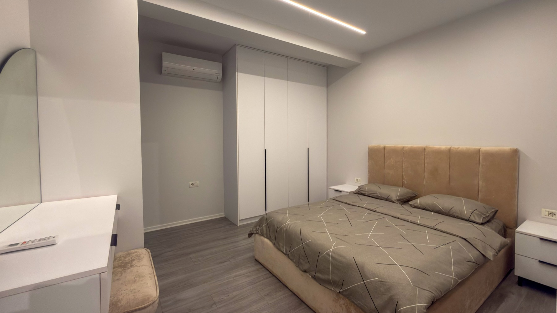 Bedroom with velvet headboard and architectural LED lighting